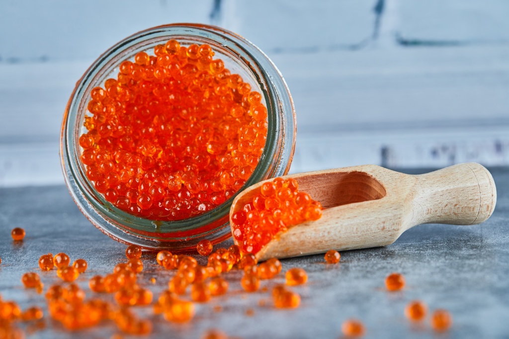a-jar-of-red-caviar-and-wooden-spoon-on-marble-background.jpg